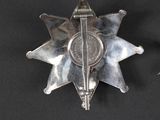 silver star badge on black background next to a pair of scissors