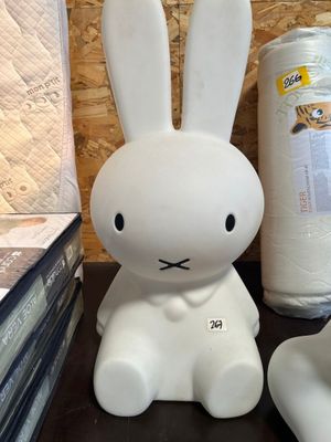 un lapin blanc assis sur une table, à côté d'un rouleau de papier toilette
