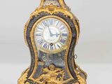 a gold and black clock sitting on a white surface