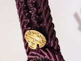 a close up of a purple rope with a gold button on it