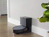 a robot that is sitting on the floor next to a potted plant