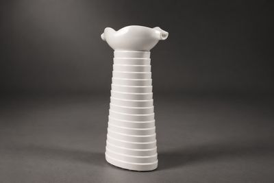 un vase blanc surmonté d'un oiseau