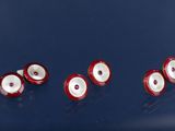 plusieurs globes oculaires rouges et blancs sont disposés en rangée sur une surface bleue