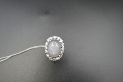 un gros plan d'une bague ornée d'une pierre blanche entourée de diamants