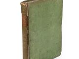 un vieux livre à la couverture verte posé sur une surface blanche