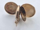 a small gold pocket watch sitting on a white surface