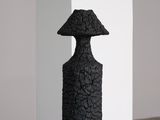 sculpture noire représentant un champignon posé sur une caisse en bois
