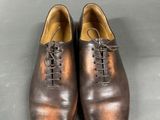 men ' s brown leather shoes with laces on a grey background