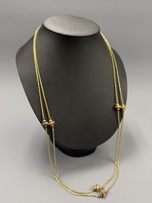 a gold necklace with three beads on a mannequin neck