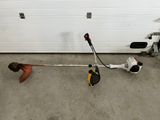 un homme en train de réparer une débroussailleuse dans un garage