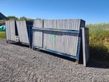 une benne à ordures posée au bord d'un chemin de gravier, à côté d'un champ