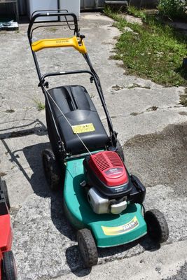 a lawn mower sitting on the sidewalk next to other lawn mowers