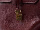 the back of a red purse with a gold lock on it