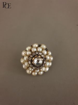 un gros plan d'une bague en perle et diamant posée sur une table