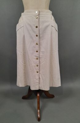 une jupe blanche avec des boutons, posée sur le torse d'un mannequin