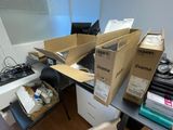 a pile of boxes sitting on top of a desk next to a chair