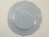 a blue plate on a white table with a blue flower on it