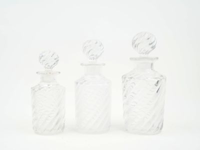 trois bouteilles en verre transparent posées les unes à côté des autres sur une surface blanche