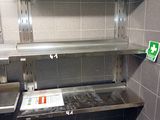 a toilet in a public restroom with a shelf above it