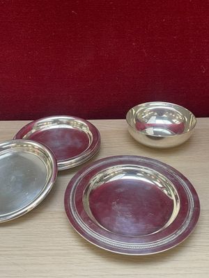 four silver plates on a wooden table with a red wall in the background