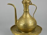 an antique brass tea pot and saucer on a tray