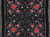 une écharpe à motifs floraux noirs et rouges, avec des franges