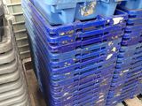 de nombreux bacs bleus empilés sur une palette dans un entrepôt