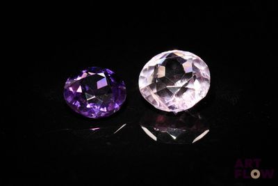 two purple and white gems sitting on top of a black surface