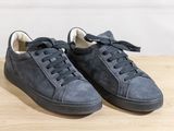 grey sued sneakers with black laces on a wooden surface