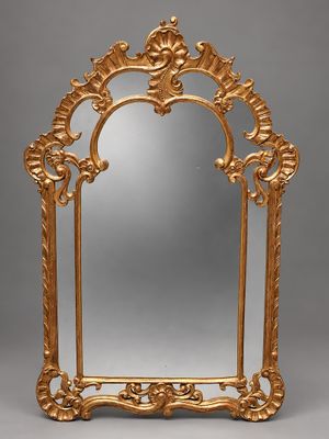 un miroir richement sculpté, avec un cadre doré sur fond gris