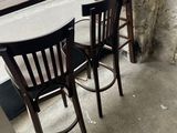 two wooden chairs and a table in front of a window