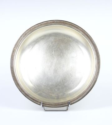 assiette en argent plaqué avec bord perlé, posée sur un support, sur fond blanc