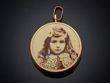 an antique photo of a young girl in a dress on a gold plated pendant