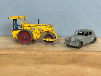 une petite voiture à côté d'un petit tracteur, posés sur une table