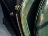 a close up of a green leather seat with a metal handle