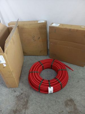 plusieurs cartons contenant des tuyaux rouges, posés les uns à côté des autres sur le sol
