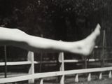 black and white photograph of a woman ' s legs hanging over a fence