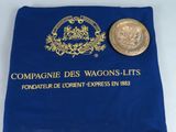 un sac bleu contenant une pièce d'or et une autre pièce posée dessus