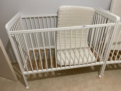 a baby crib with a white mattress in a room