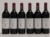 six bottles of red wine lined up in a row on a table