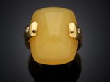 a close up of a yellow jade ring on a black surface