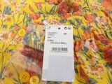 a close up of a yellow floral dress with a tag on it
