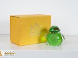 un petit vase en verre vert posé à côté d'une boîte jaune
