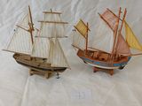 deux petits bateaux en bois exposés sur une surface blanche