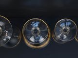 four empty wine glasses are lined up on a black surface