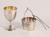 a silver cup and a spoon sitting next to each other
