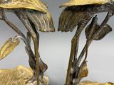 two metal birds that are sitting on a gold plate
