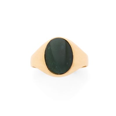 gros plan d'une bague en or avec une pierre verte