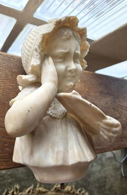a statue of a little girl holding her hand to her face