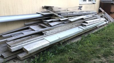 a pile of wood on the ground outside of a house